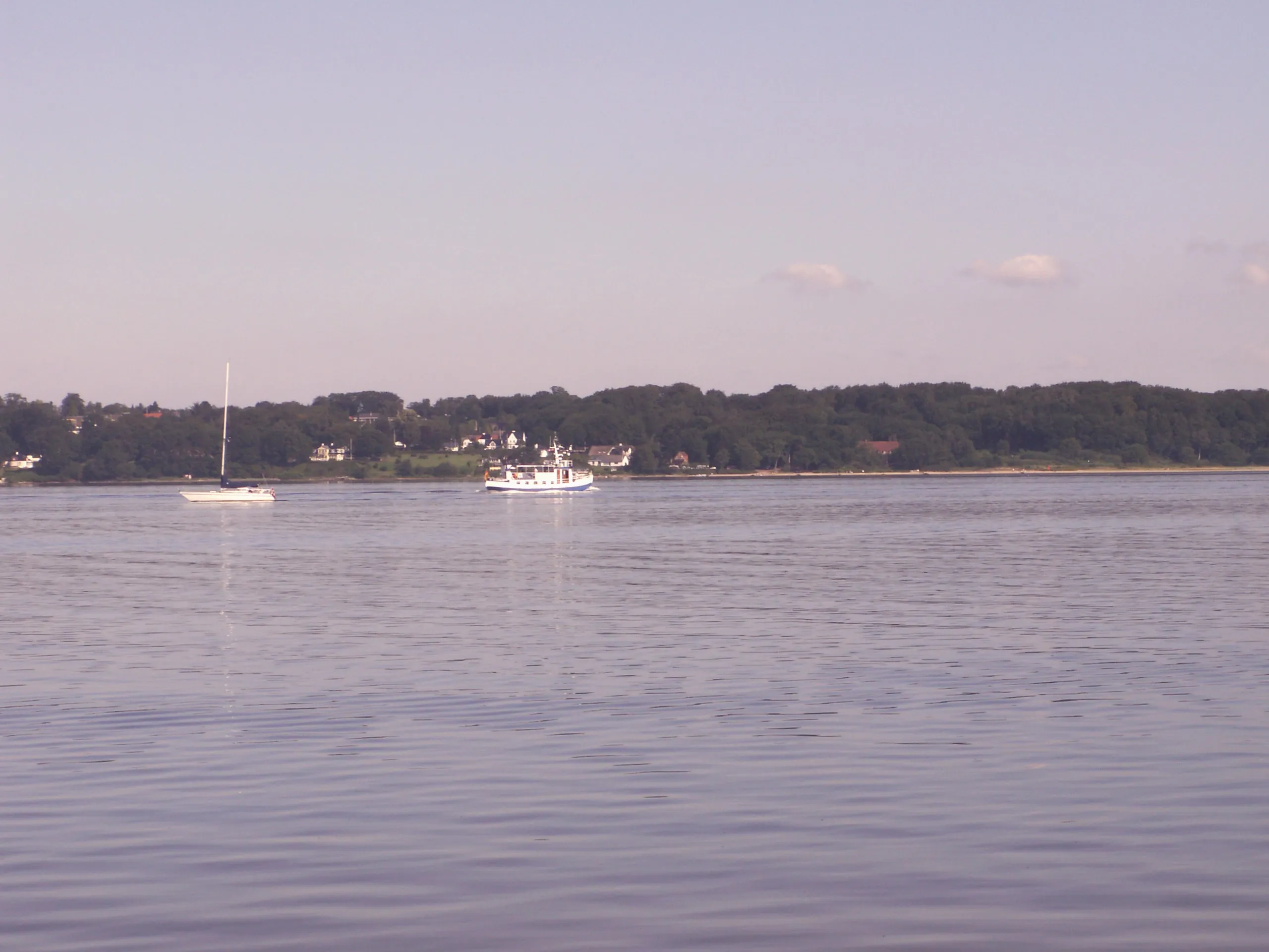 Segelboot und Motorboot vor dem gegenüberliegenden Ufer