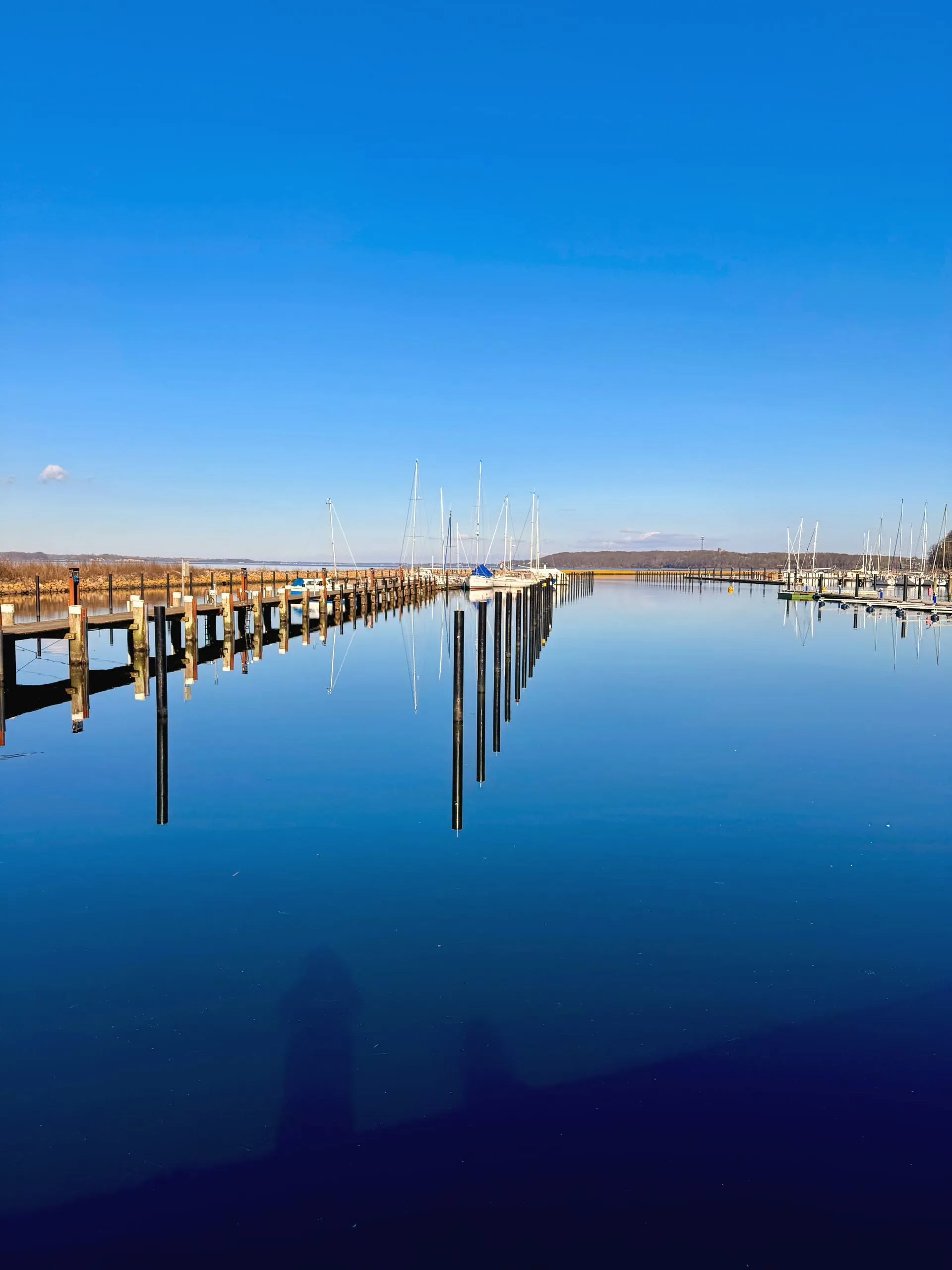 Spiegelglattes Wasser zwischen den Stegen des Yachthafens