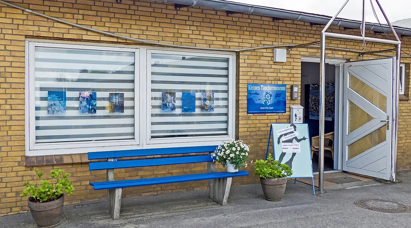 Eingang des Tauchermuseums in Fahrensodde mit blauer Bank und Blumenkübeln, 2020